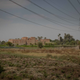 Power lines and an apartment building are visible behind a farm.
